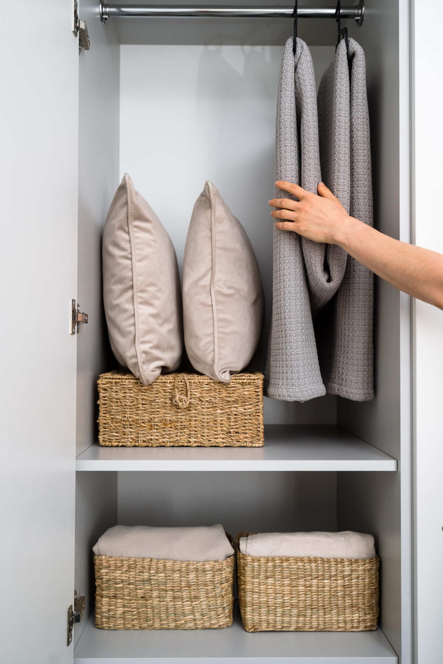 Linen closet in bedroom with pillows, blankets and wicker baskets